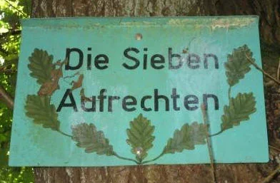 Schild mit aufgemalten Eichenblättern angebracht mit der Aufschrift „Die Sieben Aufrechten“.
