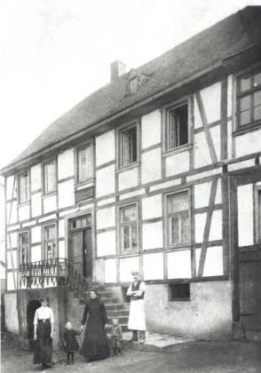 Das Haus der Bäckerei Folle im Jahre 1905 im Breiten Weg 4 in Freienohl. Vor dem Haus steht in Bäckerschürze der Gründer Anton Folle mit seiner Familie.